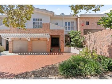 Inviting townhome with brick accents, a two-car garage, and lush landscaping at 711 S Oregon Ave, Tampa, FL 33606