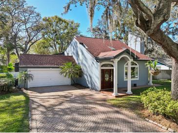 Charming home featuring a brick driveway, attached garage, and an arched entryway with white columns at 14910 Northwood Village Ln, Tampa, FL 33613