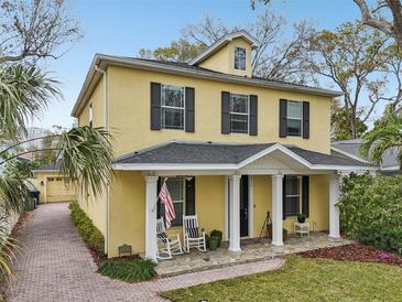 Charming yellow two-story home with a welcoming front porch and manicured landscaping at 2915 W Bay View Ave, Tampa, FL 33611