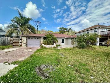 Charming single-story home with stone accents, a garage, and mature landscaping under a partly cloudy sky at 8537 Horizon Ln, Hudson, FL 34667