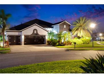 Charming two-story home boasting lush landscaping and a spacious three-car garage at twilight at 6927 Crestpoint Dr, Apollo Beach, FL 33572