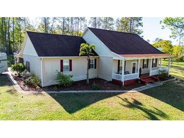 Charming single-story home featuring a covered front porch and beautiful landscaping at 15124 Appaloosa Hills Dr, Dade City, FL 33523