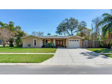 Inviting single-story home with a well-manicured lawn, covered porch, and attached garage at 2823 St Croix Dr, Clearwater, FL 33759
