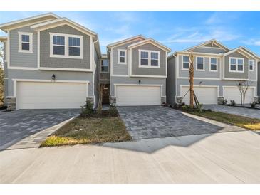 Charming townhomes feature light gray siding, a one-car garage, and a welcoming paved driveway at 31480 Woodland Race Loop, Wesley Chapel, FL 33545