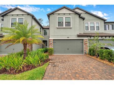 Beautiful townhome featuring a two-car garage, a brick paver driveway, and well-manicured landscaping at 5086 San Martino Dr, Wesley Chapel, FL 33543