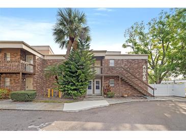 Two-story brick building with palm trees, exterior stairs, and sidewalk at 10423 Carrollbrook Cir # 102, Tampa, FL 33618