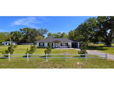 Charming single-story home with manicured lawn, white picket fence, and inviting curb appeal at 1413 Lithia Pinecrest Rd, Brandon, FL 33511