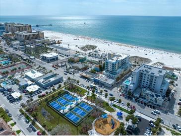 Aerial view of beachfront condos, tennis courts, and a playground near the ocean at 15 Avalon St # 303, Clearwater Beach, FL 33767