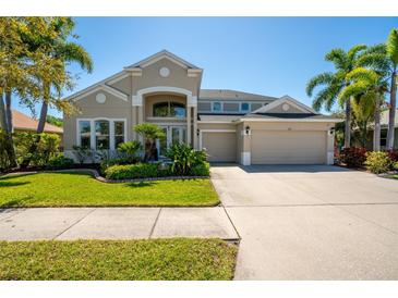 Charming two-story home featuring a well-manicured lawn, complemented by lush tropical landscaping and a spacious three-car garage at 309 Royal Bonnet Dr, Apollo Beach, FL 33572