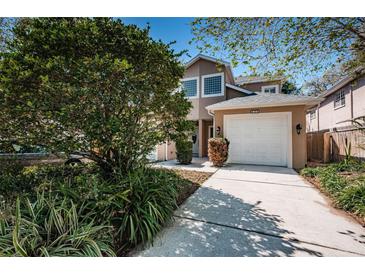 Charming home exterior features a well-manicured lawn, a two-car garage, and lush landscaping at 409 S Arrawana Ave, Tampa, FL 33609