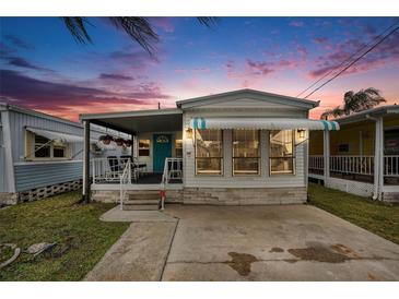 Charming single-story home featuring a cozy covered porch and neat landscaping at sunset at 647 Yawl Ln, Palm Harbor, FL 34683