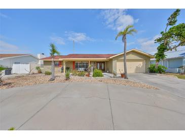 Charming single-story home featuring a two-car garage, a circular driveway, and palm trees in the front yard at 727 Flamingo Dr, Apollo Beach, FL 33572