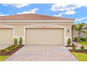 Attached two-car garage with decorative driveway and landscaping provides attractive curb appeal at 20387 Symphony Pl, Venice, FL 34293