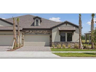 Beautiful home exterior with stone accents, paver driveway, and well-maintained landscaping at 35593 Stableton Ln, Zephyrhills, FL 33541