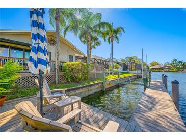 Inviting waterfront home featuring a private wooden dock, boat lift, and seating area for enjoying scenic water views at 5806 Dory Way, Tampa, FL 33615