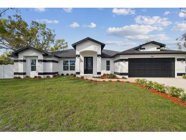 Striking single-story home featuring a black and white exterior, two car garage and well-manicured lawn at 104 1St Ne Ave, Lutz, FL 33549