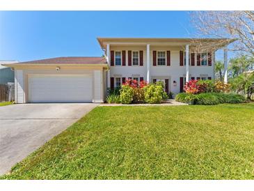 Traditional two-story home with white columns, shutters, attached garage and well manicured lawn at 15703 Jericho Dr, Odessa, FL 33556