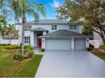 Charming two-story home featuring a three car garage, red front door, and mature landscaping at 4859 Augusta Ave, Oldsmar, FL 34677