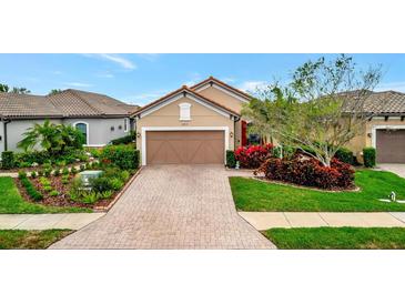 Charming home featuring a well-manicured lawn, mature landscaping, and a brick paved driveway at 10213 Saint Francis Ter, Palmetto, FL 34221