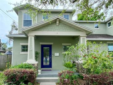 Charming two-story home featuring a covered front porch, blue door, and lush landscaping at 208 W Amelia Ave # 1, Tampa, FL 33602