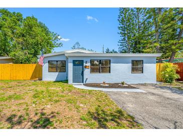 Charming single-story home features a well-manicured lawn, a classic exterior, and a vibrant yellow fence at 217 Emerald Ln, Largo, FL 33771
