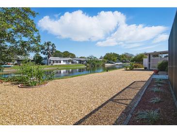 Landscaped backyard featuring low-maintenance gravel and a serene waterfront view on a sunny day at 3729 Sail Dr, New Port Richey, FL 34652