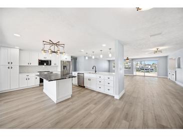 Bright kitchen features white cabinetry, stainless steel appliances, a large island, and modern lighting at 6410 3Rd Palm Pt, St Pete Beach, FL 33706