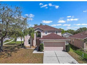 Inviting two-story home with a manicured lawn and a spacious two-car garage, nestled under a bright, partly cloudy sky at 12802 Lake Vista Dr, Gibsonton, FL 33534