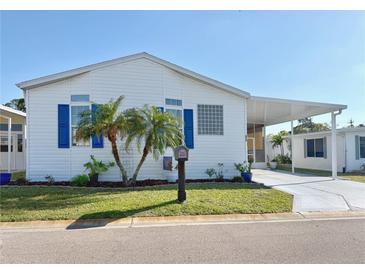 Charming single-story home with white siding, blue shutters, palm trees and covered parking at 272 S Port Royal Ln, Apollo Beach, FL 33572
