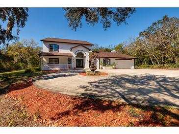 Stunning two-story home with a circular driveway and a decorative fountain at 3030 Cedar Trce, Tarpon Springs, FL 34688