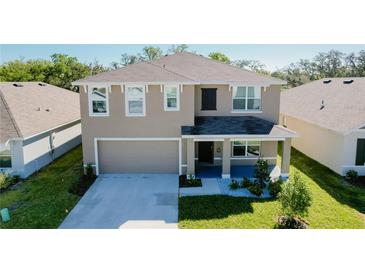 Charming two-story home with a well-manicured lawn, inviting front porch, and two-car garage at 7711 Rosewood Garden Loop, Tampa, FL 33637