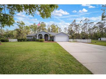 Charming single-story home with a well-manicured lawn, a long driveway, and an American flag on display at 1126 Oxbow Rd, Wimauma, FL 33598