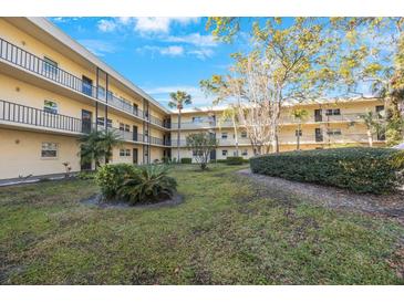 Exterior view of a condo building surrounding a courtyard with lush green landscaping and mature trees at 11485 Oakhurst Rd # 111, Largo, FL 33774