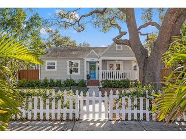 Charming home featuring a well-manicured lawn, a white picket fence, and a inviting blue door at 1205 13Th N St, St Petersburg, FL 33705