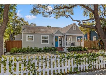 Charming one-story home featuring a blue front door, inviting porch, and lovely white picket fence at 1205 13Th N St, St Petersburg, FL 33705