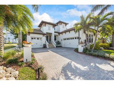 Beautiful two-story white home with a brick driveway and lush tropical landscaping at 3006 Christophers Watch Ln, Ruskin, FL 33570