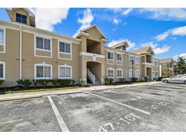 Beige two-story condo building with multiple units and visible parking spots at 6447 Cypressdale Dr # 202, Riverview, FL 33578