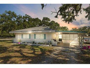Charming single-story home featuring a carport, brick accents, and well-maintained landscaping under a picturesque sunset at 7143 Sealawn Dr, Spring Hill, FL 34606
