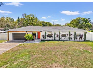 Charming home with an eye-catching red door, modern paint, a well-manicured lawn, and a beautiful landscape design at 1110 S Pine Lake Dr, Tampa, FL 33612