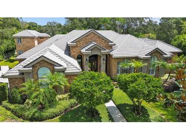 Stunning brick home featuring lush landscaping, manicured bushes, and a tiled roof at 16211 Villarreal De Avila, Tampa, FL 33613