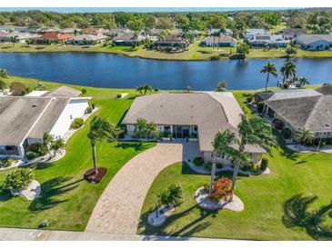 Aerial view of a well-maintained home with a brick driveway, lush lawn and mature landscaping near a canal at 1707 Wedge Ct, Sun City Center, FL 33573