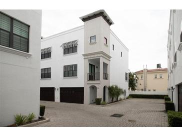 Charming three-story townhouse featuring white stucco, dark wood garage doors, and well-maintained landscaping at 224 S Audubon Ave, Tampa, FL 33609