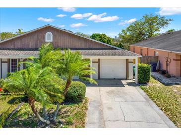 Charming home exterior featuring a two-car garage, lush landscaping, and a well-maintained driveway at 8551 N Hyaleah Rd, Tampa, FL 33617
