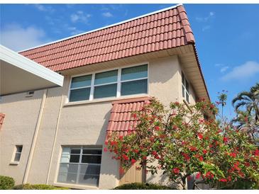 Beige two-story house with a red tile roof and a flowering shrub in front of a window at 10039 62Nd N Ave # 14, St Petersburg, FL 33708