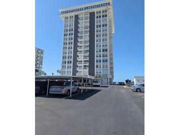 Modern high-rise condo building with covered parking on a sunny day at 17408 Gulf Blvd # 201, Redington Shores, FL 33708