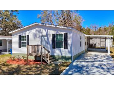 Charming home with white siding, black shutters, and a covered carport for convenient parking at 18079 Carrolwood Dr, Brooksville, FL 34604