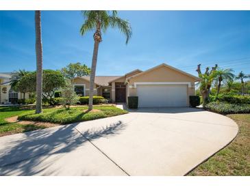 Charming single-story home with well-manicured lawn, palm trees, and a spacious driveway to the two-car garage at 1996 Promenade Way, Clearwater, FL 33760