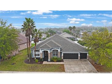 Charming single-story home with a three-car garage, stone accents, and lush landscaping at 18413 Eastwyck Dr, Tampa, FL 33647