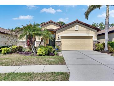 Beautiful tan home with stone accents, a two-car garage, a tile roof and professional landscaping at 329 Laurel Falls Dr, Apollo Beach, FL 33572