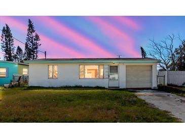 Charming single-story home with a well-maintained lawn and attached garage under a vivid sunset at 596 S Bayshore Dr, Madeira Beach, FL 33708